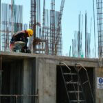 man kneeling on unfinished building during daytime