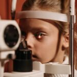 A young girl undergoing an eye exam with advanced ophthalmology equipment, focusing on vision care.